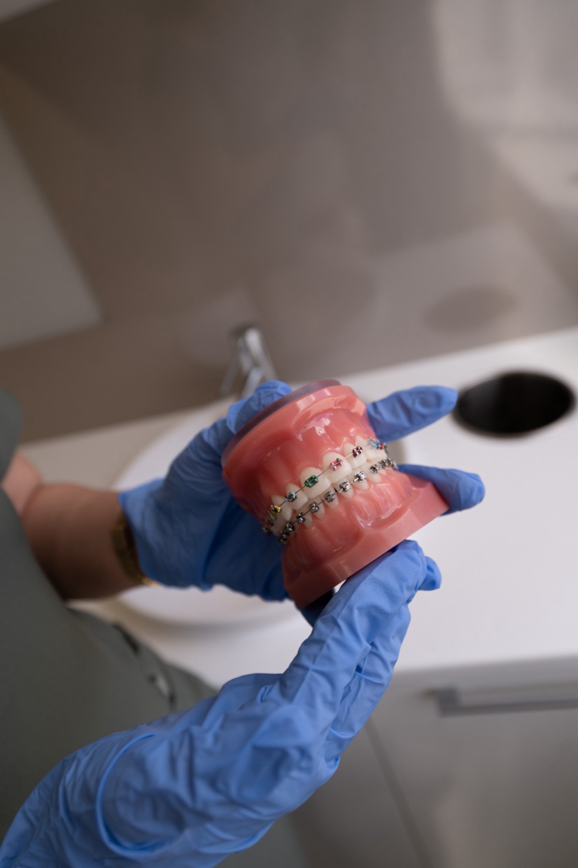 Gloved hands holding a teeth model with braces